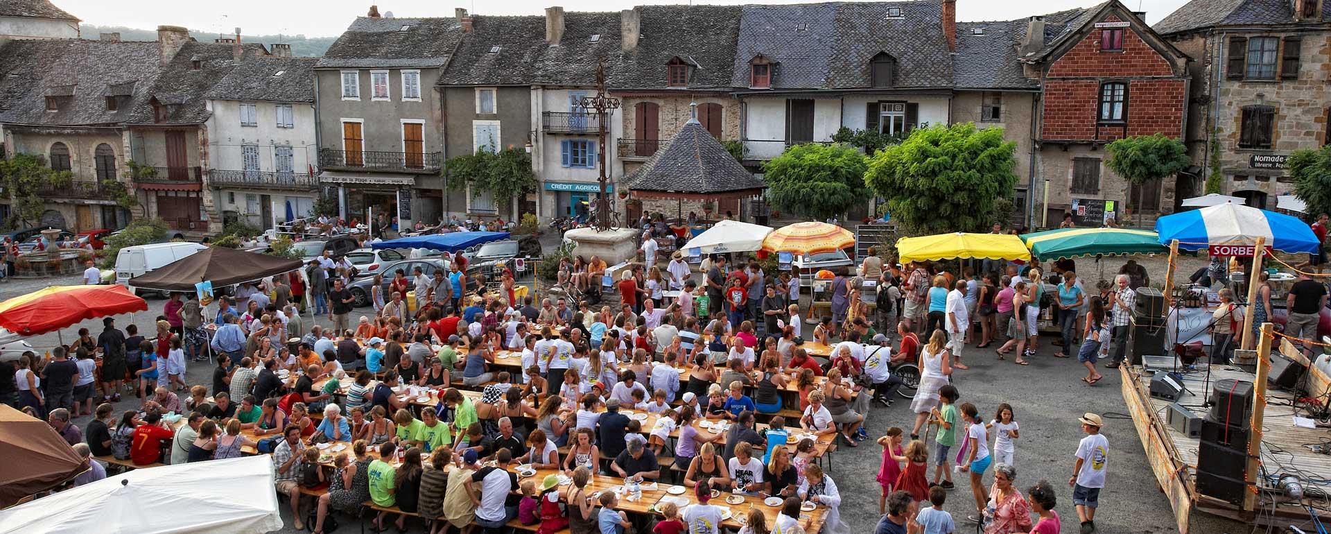 Scène vivante du marché de Najac, un des plus beaux villages de France, avec des étals colorés, des habitants et des visiteurs profitant de l’événement local.