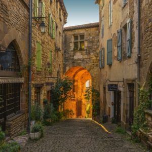Ruelle médiévale de Cordes-sur-Ciel au coucher du soleil, avec ses maisons en pierre et son atmosphère pittoresque.